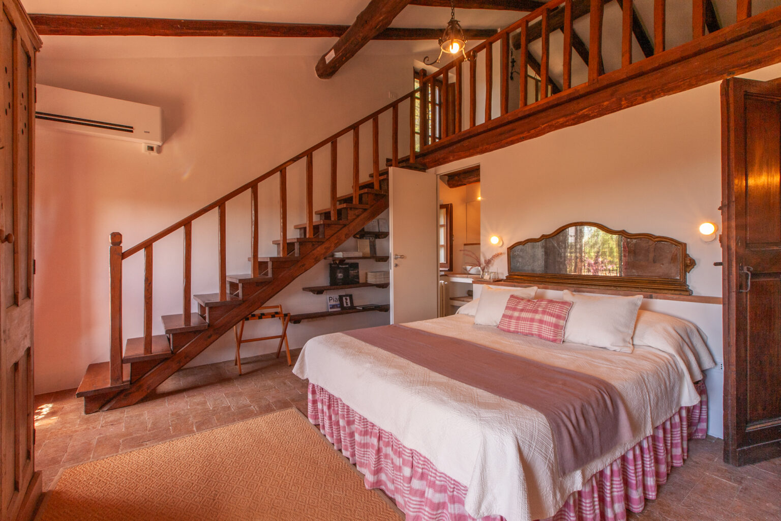 Cozy bedroom interior featuring a large bed with decorative pillows, wooden accents, and a staircase leading to an upper loft area, designed for comfort and relaxation. | Only on SopranoVillas
