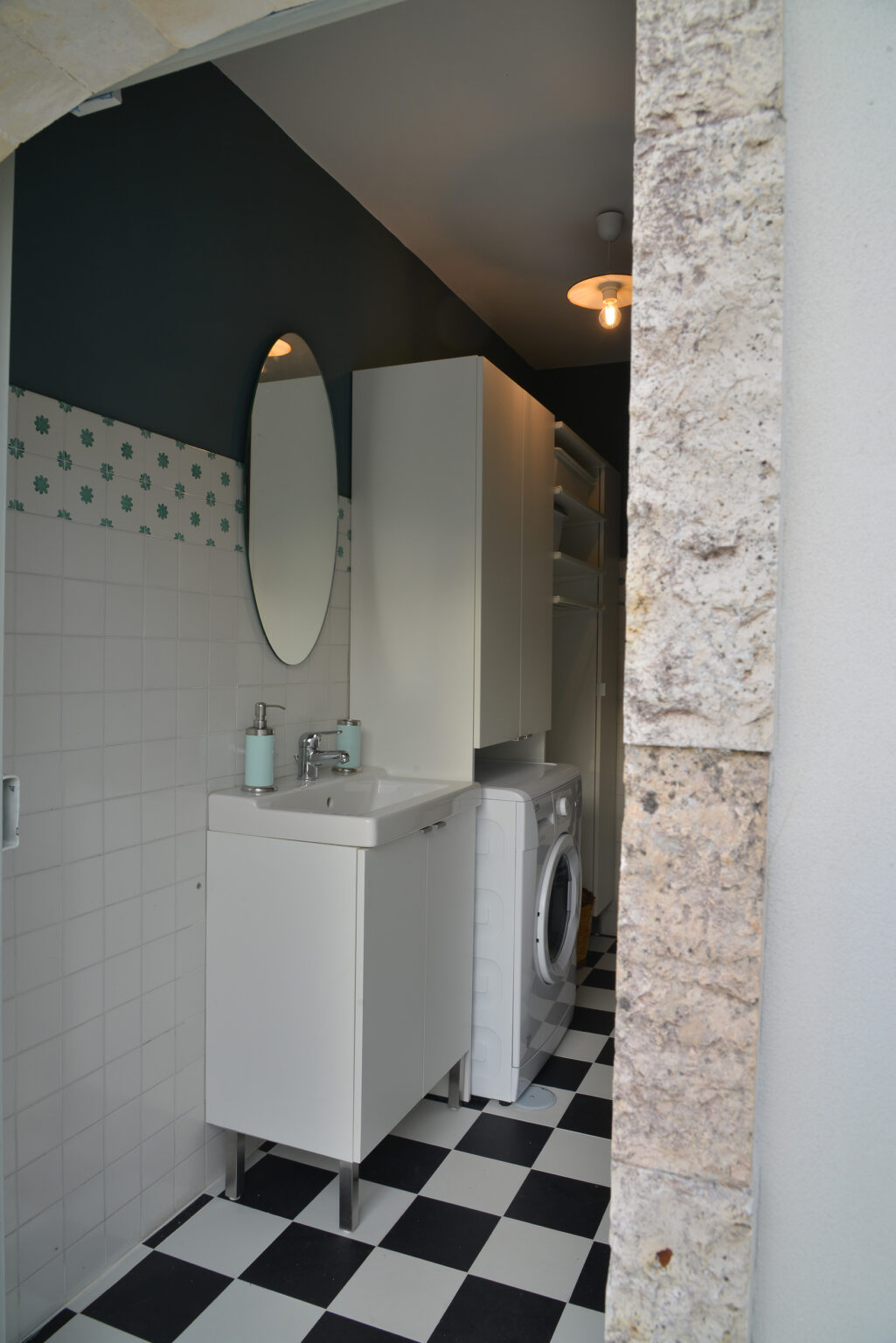 Modern laundry room featuring a compact sink, mirror, and washing machine, with stylish decor including patterned walls and natural stone accents. | Only on SopranoVillas
