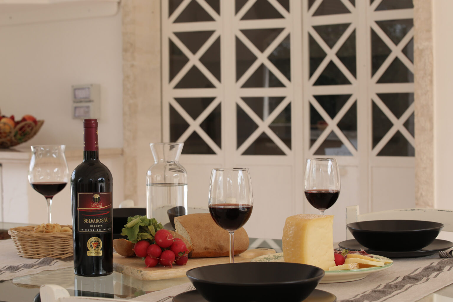 Elegant dining setup featuring red wine, cheese, fresh strawberries, and water in a modern kitchen with a stylish backdrop. Perfect for a romantic dinner or gathering. | Only on SopranoVillas