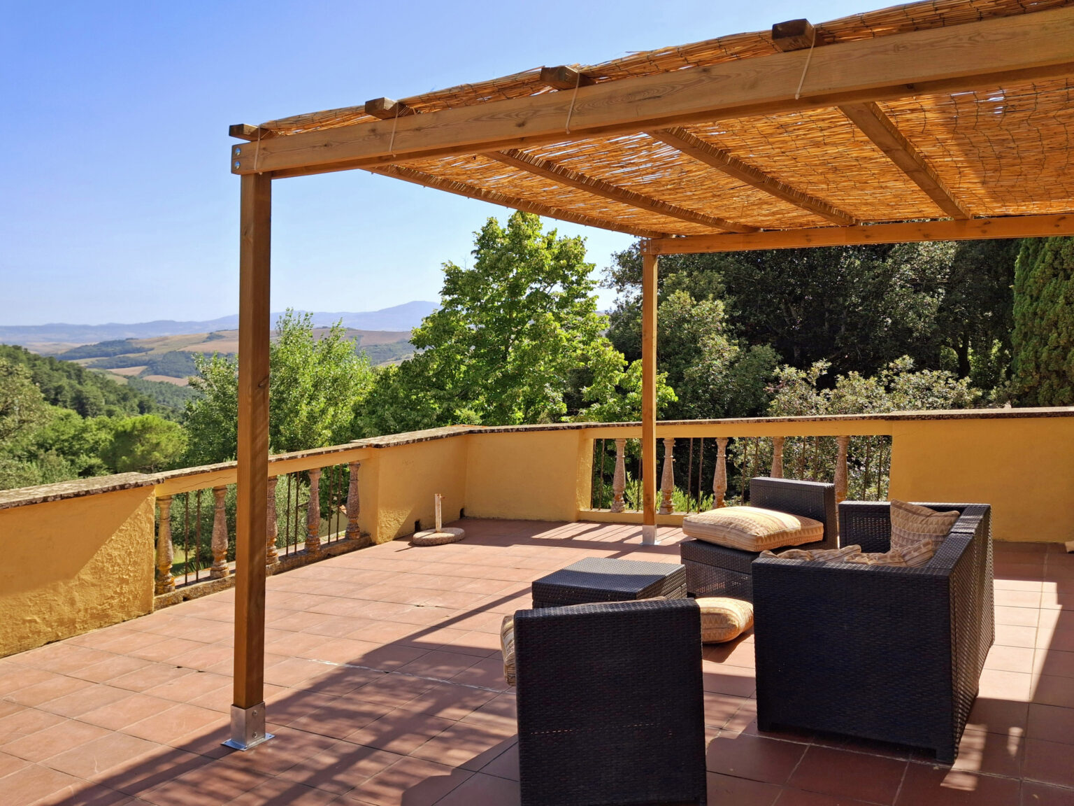 Spacious outdoor terrace with a wooden pergola, featuring comfortable seating and a scenic view of lush greenery and rolling hills. Ideal for relaxation and enjoying nature. | Only on SopranoVillas