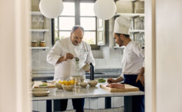 Two chefs preparing a gourmet dish in a modern kitchen, featuring fresh ingredients on a counter and stylish decor.