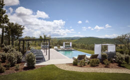Luxurious outdoor pool area with lounge chairs, cabanas, and scenic mountain views, surrounded by lush greenery and a clear blue sky. Ideal for relaxation and leisure in a serene setting.