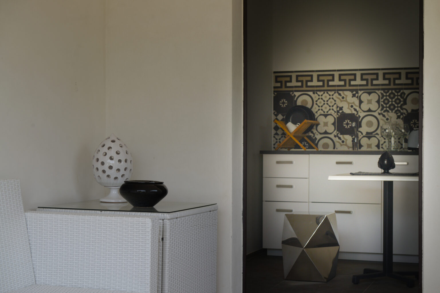 Modern interior design featuring a minimalist kitchen with patterned backsplash, sleek cabinetry, and decorative vases on a white table. | Only on SopranoVillas