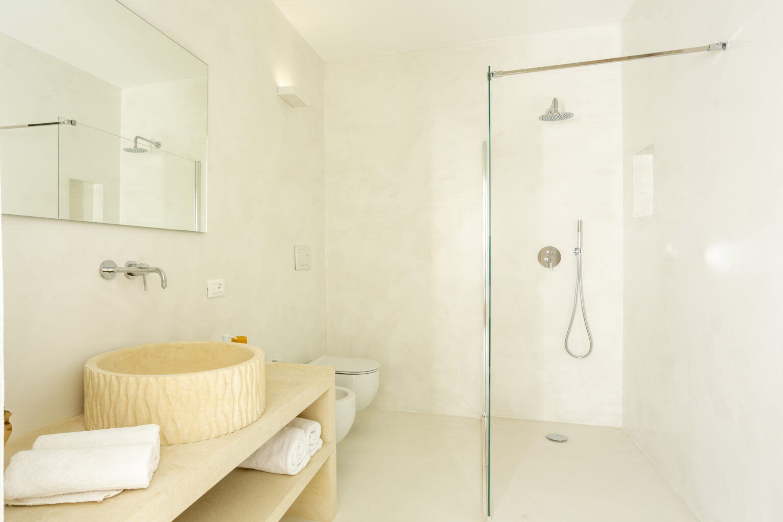 Modern bathroom with a glass shower enclosure, minimalist design, wooden vanity with a round sink, and neatly arranged towels. Bright and airy atmosphere with neutral tones. | Only on SopranoVillas