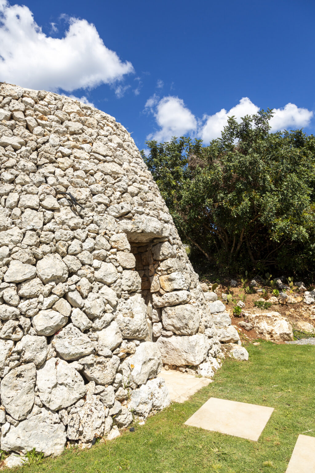 Stone structure with a doorway surrounded by lush greenery, showcasing traditional dry-stone construction techniques. | Only on SopranoVillas