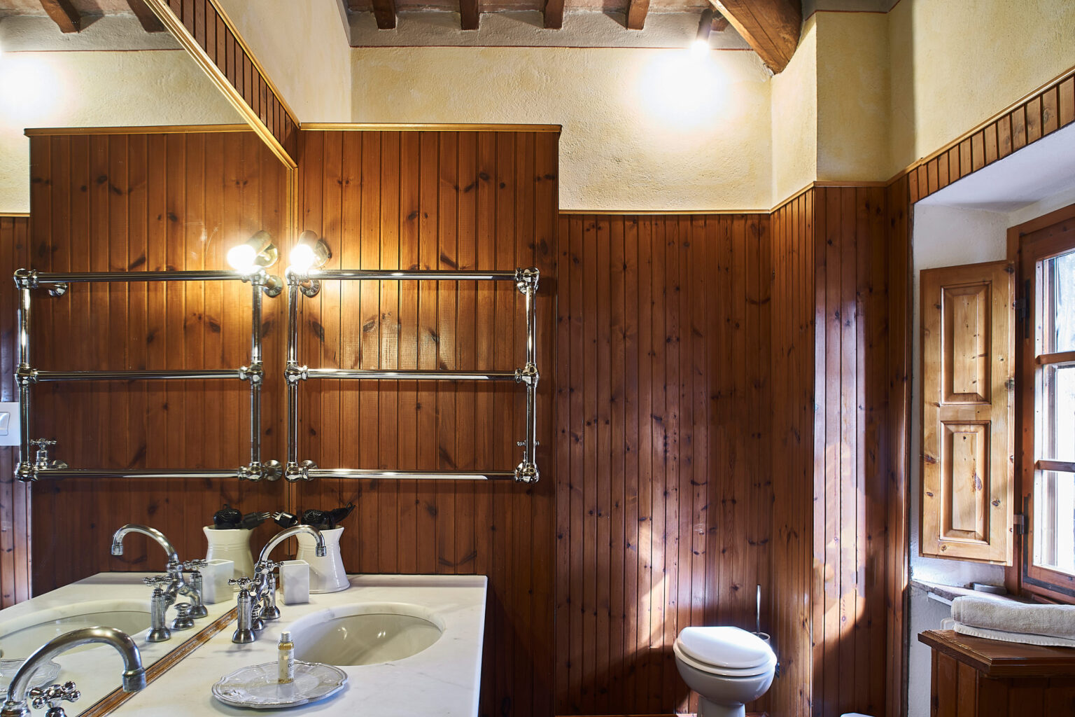 Modern bathroom design featuring wooden paneling, dual sinks, elegant fixtures, and natural lighting from a window. Ideal for showcasing contemporary interior aesthetics. | Only on SopranoVillas