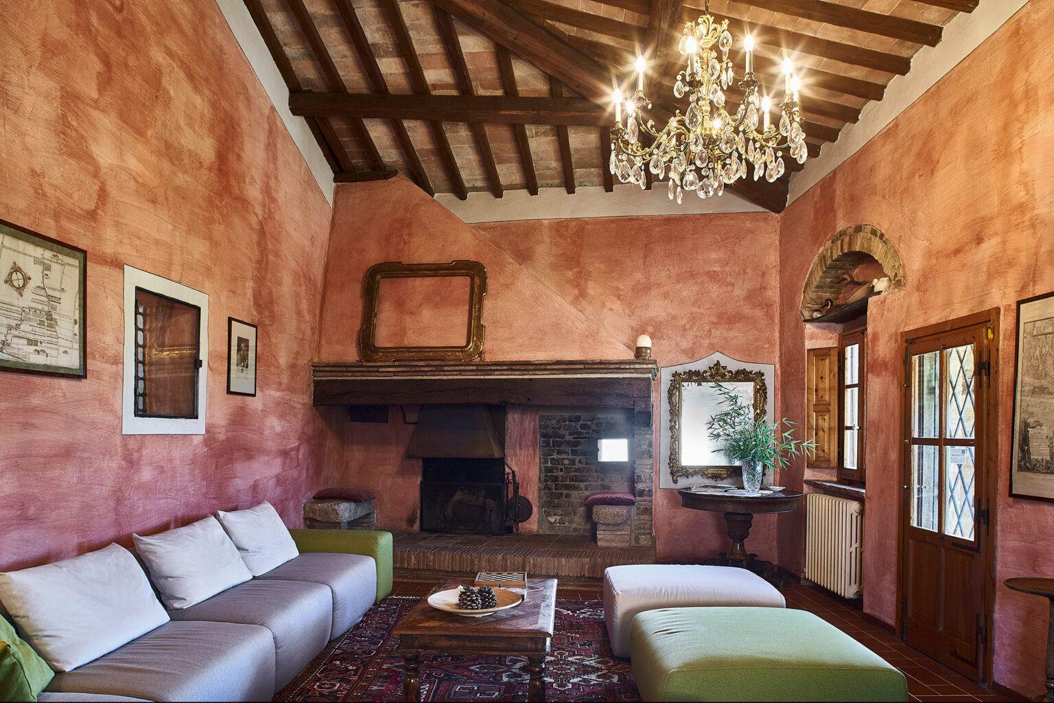 Cozy living room featuring rustic decor, a wooden beam ceiling, and a chandelier, with a fireplace and comfortable seating. The walls are painted in warm tones, creating an inviting atmosphere. | Only on SopranoVillas