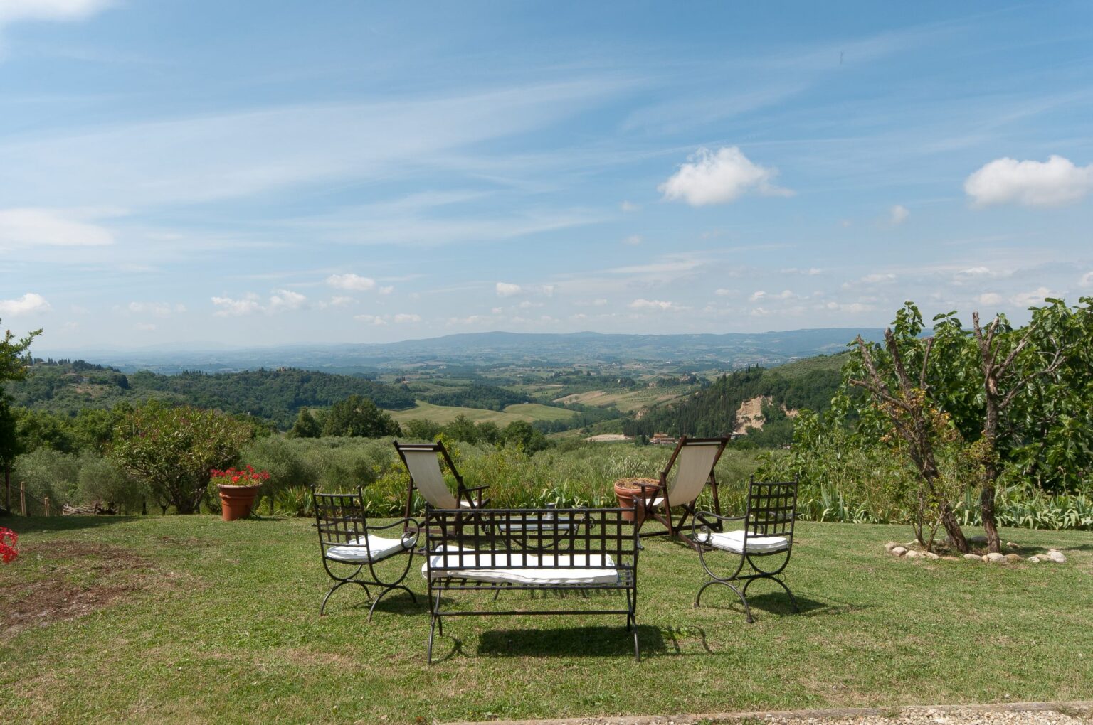 Scenic view of a landscaped garden with outdoor seating, overlooking rolling hills and a clear blue sky, ideal for relaxation and enjoying nature. | Only on SopranoVillas