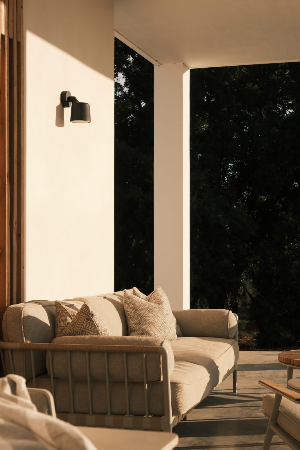 Cozy living room with a beige sofa adorned with decorative pillows, positioned near large windows that let in natural light and offer a view of the outdoors. | Only on SopranoVillas
