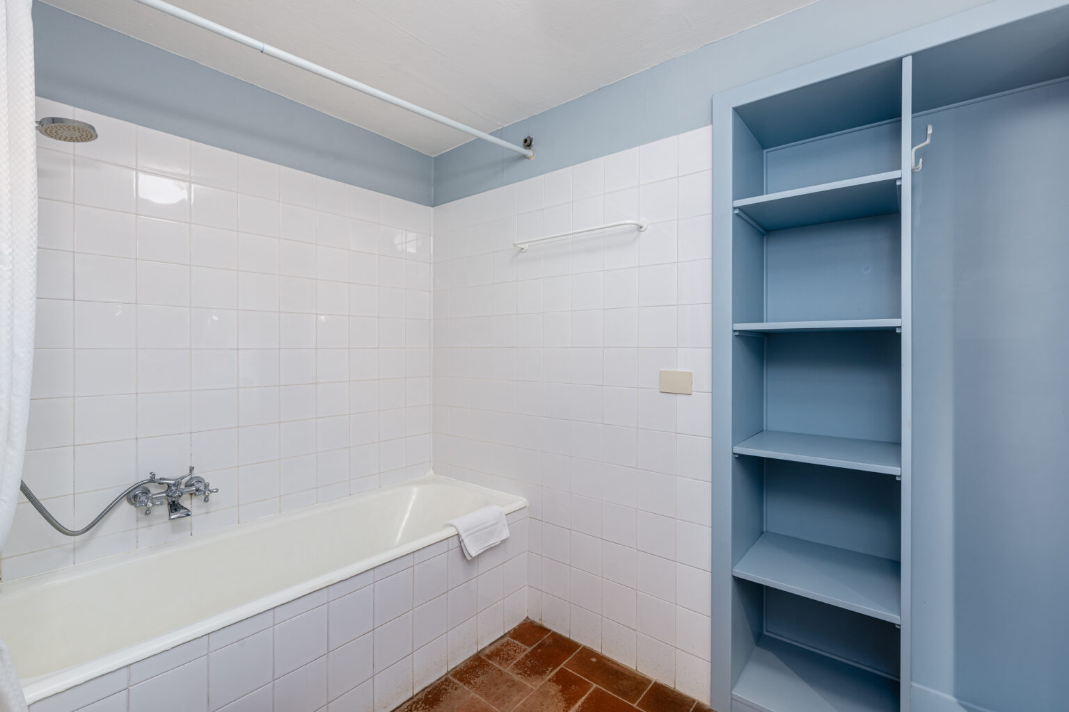Modern bathroom featuring a white bathtub, blue accent walls, and a built-in shelving unit. The space is well-lit and designed for functionality and comfort. | Only on SopranoVillas