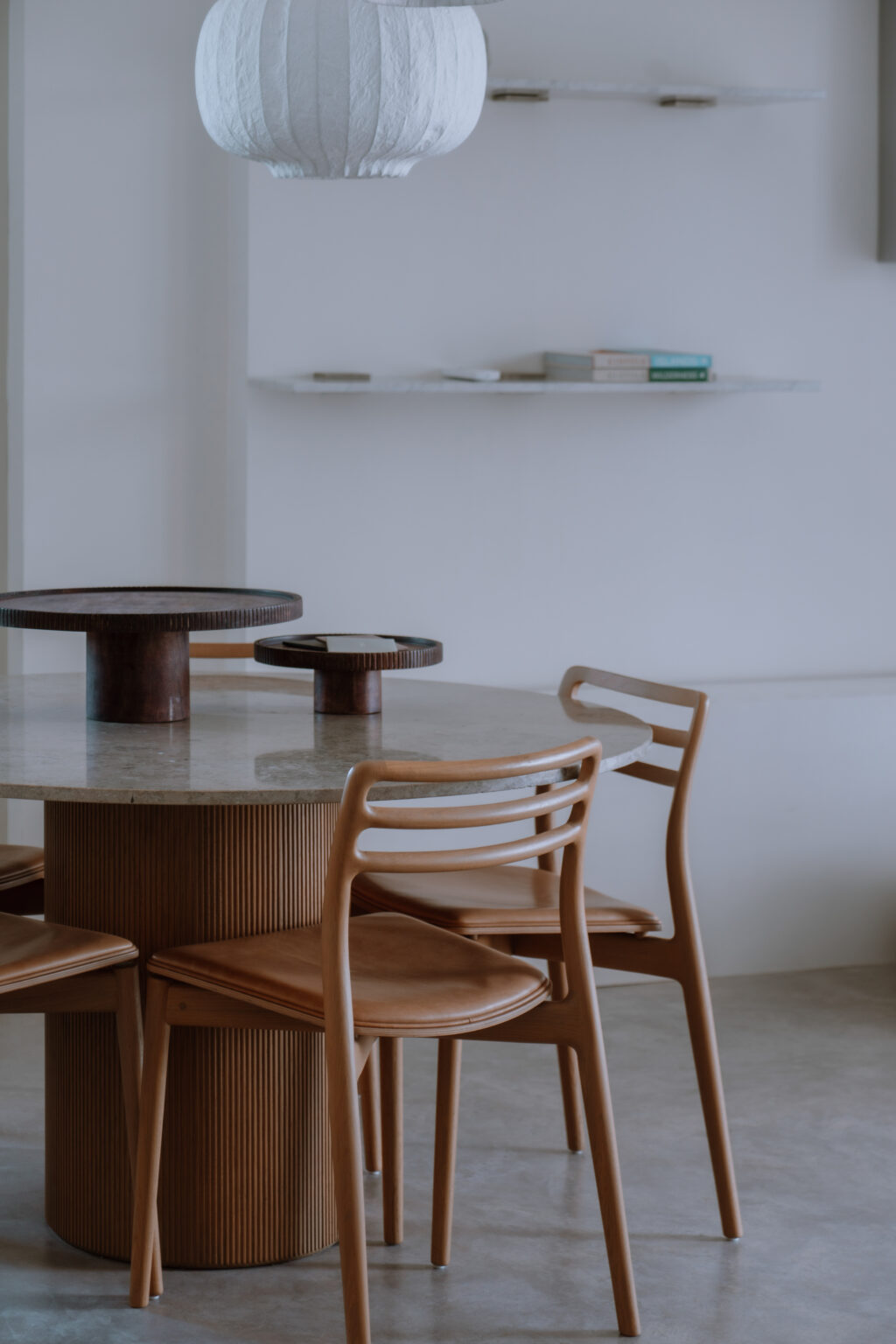 Modern dining room featuring a round marble table with wooden accents and minimalist chairs, set against a neutral wall. | Only on SopranoVillas
