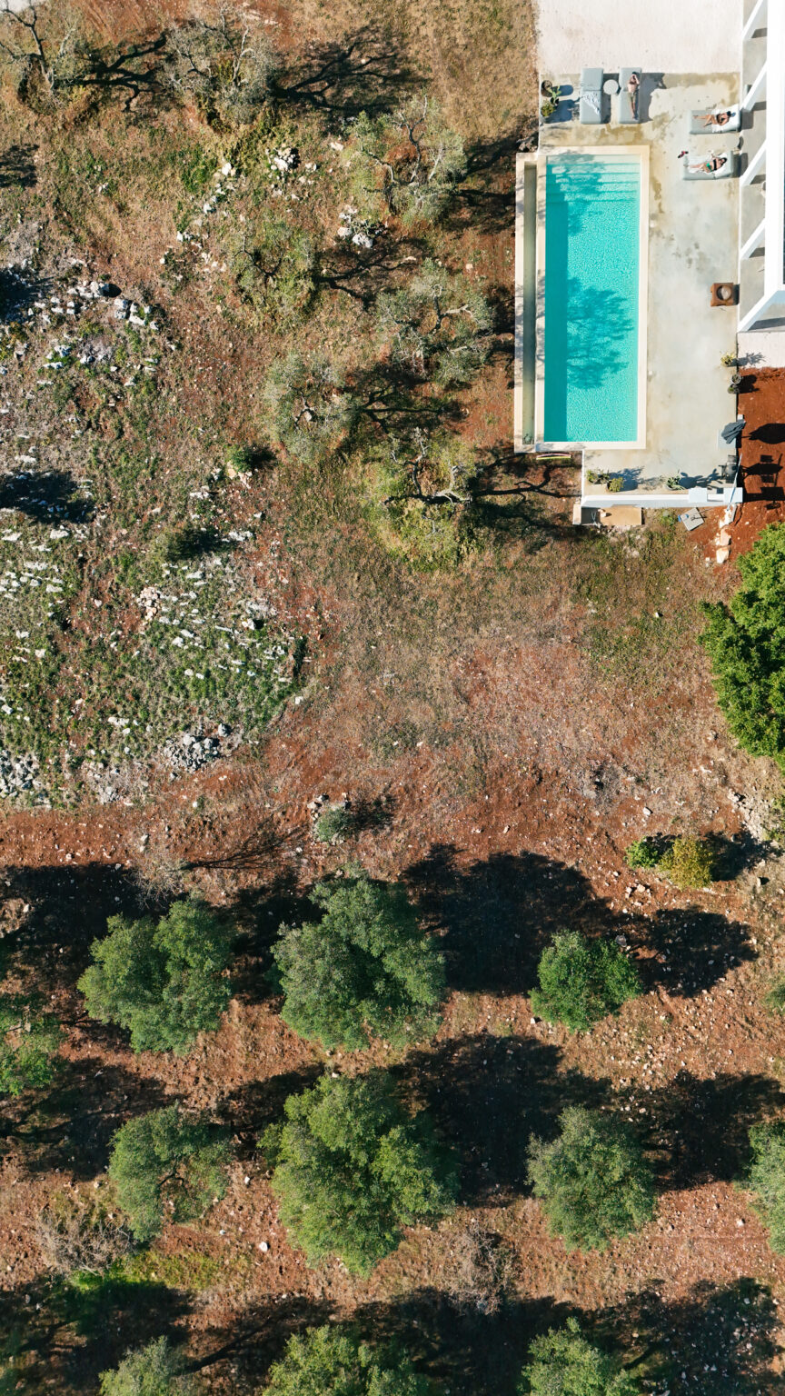 Aerial view of a cleared land area with scattered rocks and sparse vegetation, featuring a small building in the corner and surrounded by trees. | Only on SopranoVillas
