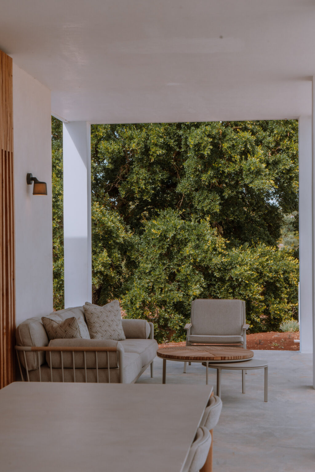 Cozy outdoor seating area featuring a plush sofa and armchair, surrounded by lush greenery, creating a serene and inviting atmosphere for relaxation. | Only on SopranoVillas
