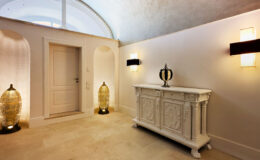 Elegant hallway featuring a white ornate console table, decorative lamps, and an arched ceiling, creating a sophisticated entryway ambiance.