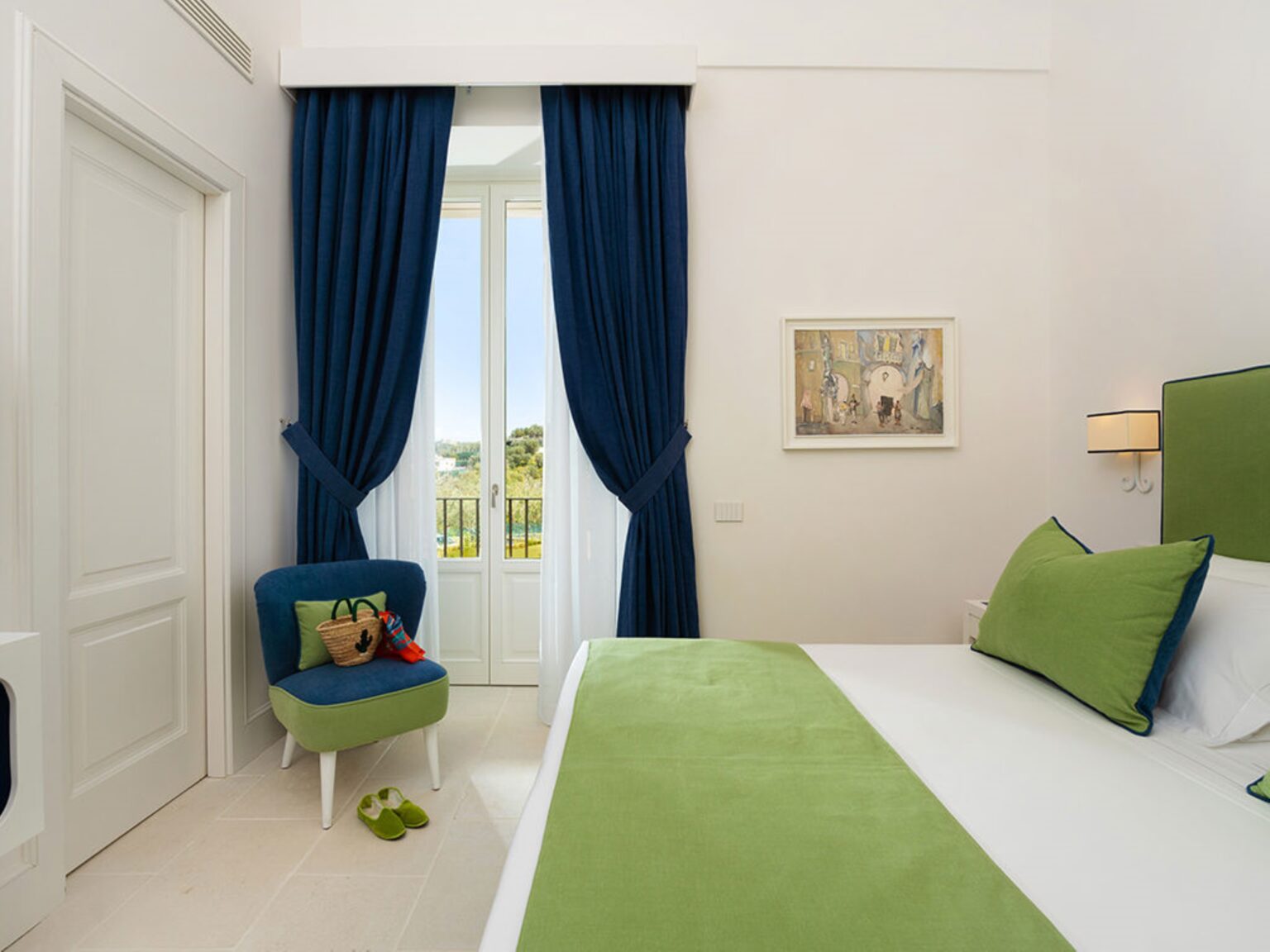 Modern bedroom interior featuring green accents, blue curtains, and a cozy chair, with natural light streaming through a large window. Ideal for showcasing stylish home decor and comfortable living spaces. | Only on SopranoVillas