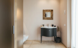 Modern bathroom interior featuring a sleek black vanity, a stylish mirror, and neutral wall colors. The space is well-lit with natural light, showcasing elegant tile flooring and minimalistic decor.
