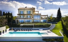 Luxurious villa featuring a modern design with large glass windows, surrounded by lush greenery and a serene pool area. The property includes a spacious terrace and relaxing outdoor seating, ideal for enjoying scenic views and outdoor living.
