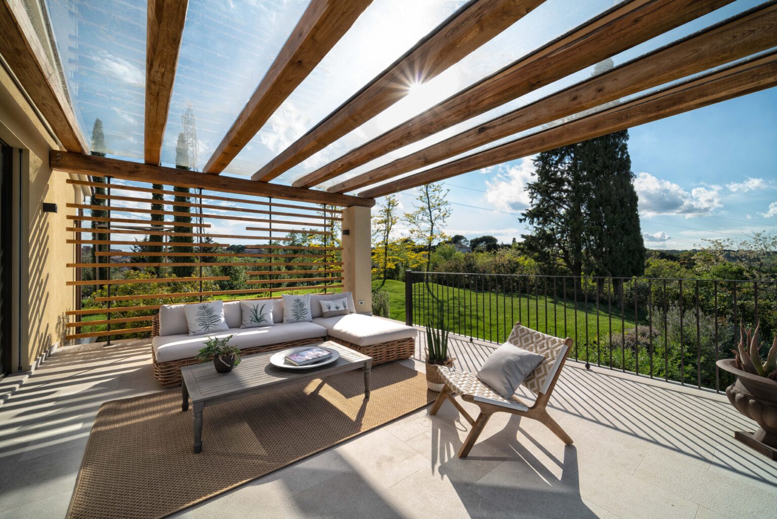 Modern outdoor patio with wooden beams, comfortable seating, and a scenic view of lush greenery. Ideal for relaxation and entertaining. Natural light enhances the inviting atmosphere. | Only on SopranoVillas