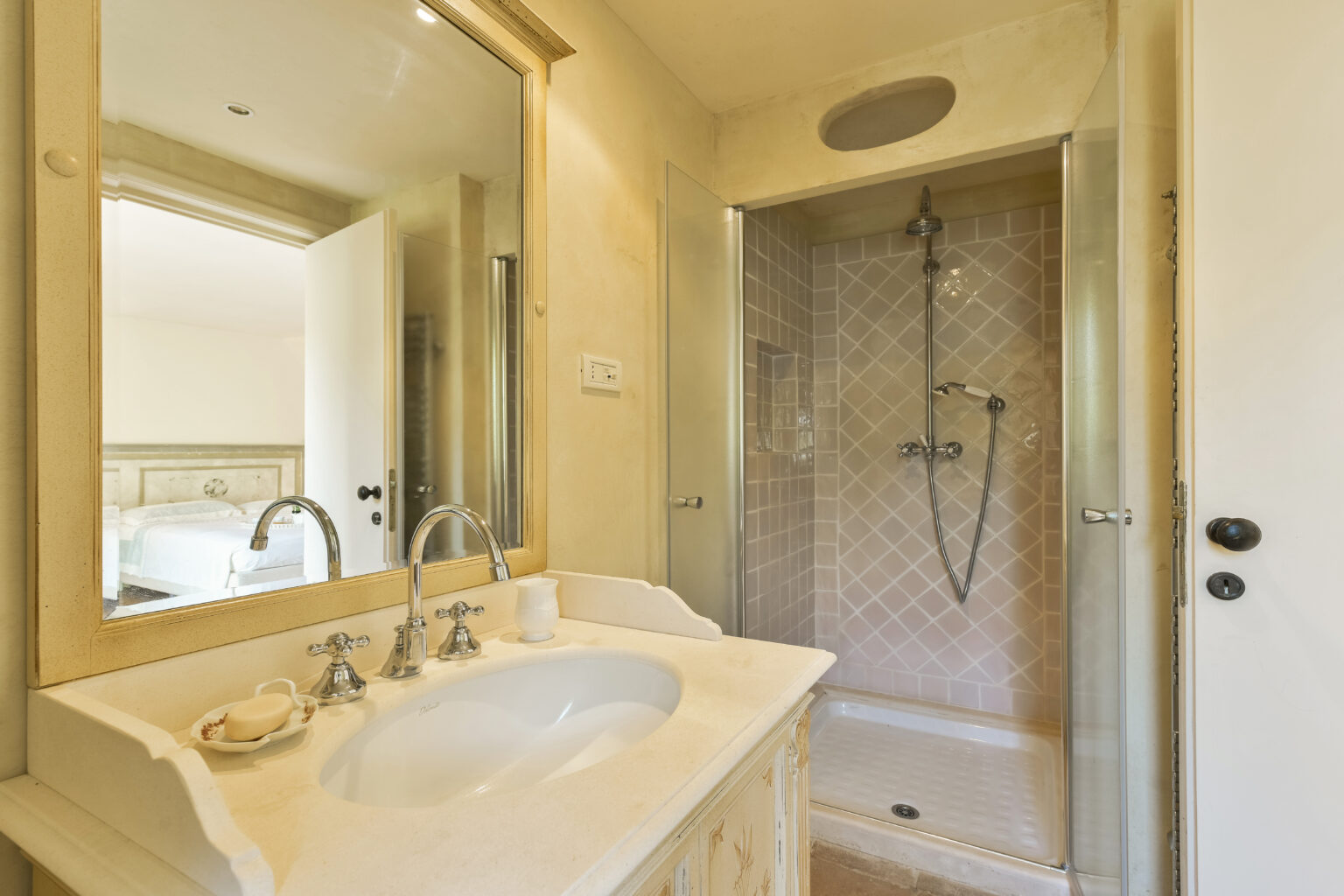 Modern bathroom featuring a stylish shower with dual showerheads, a spacious sink with elegant fixtures, and a large mirror, creating a bright and inviting atmosphere. | Only on SopranoVillas