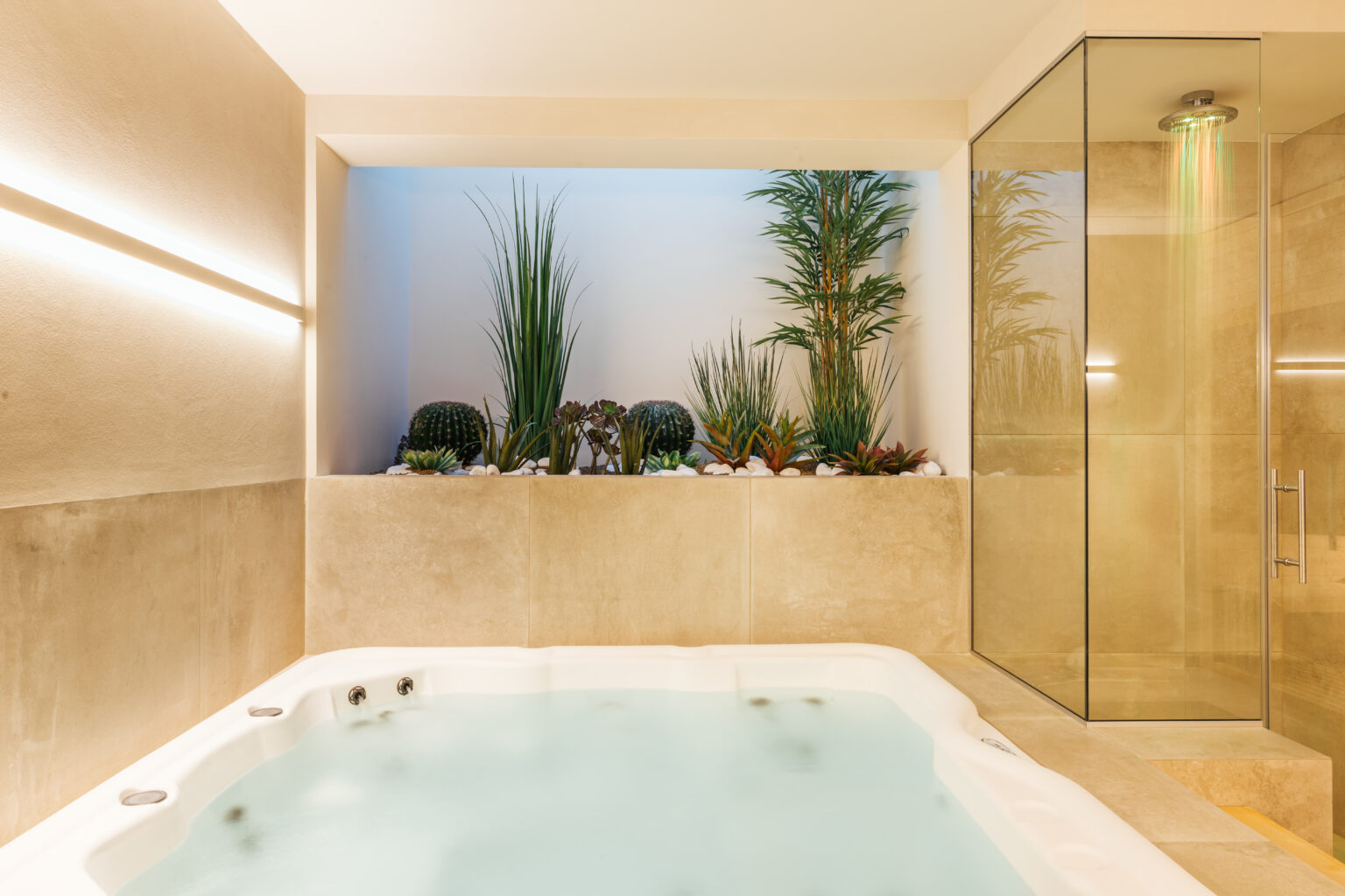 Modern spa area featuring a luxurious hot tub, surrounded by elegant plants and a glass shower enclosure, designed for relaxation and wellness. | Only on SopranoVillas