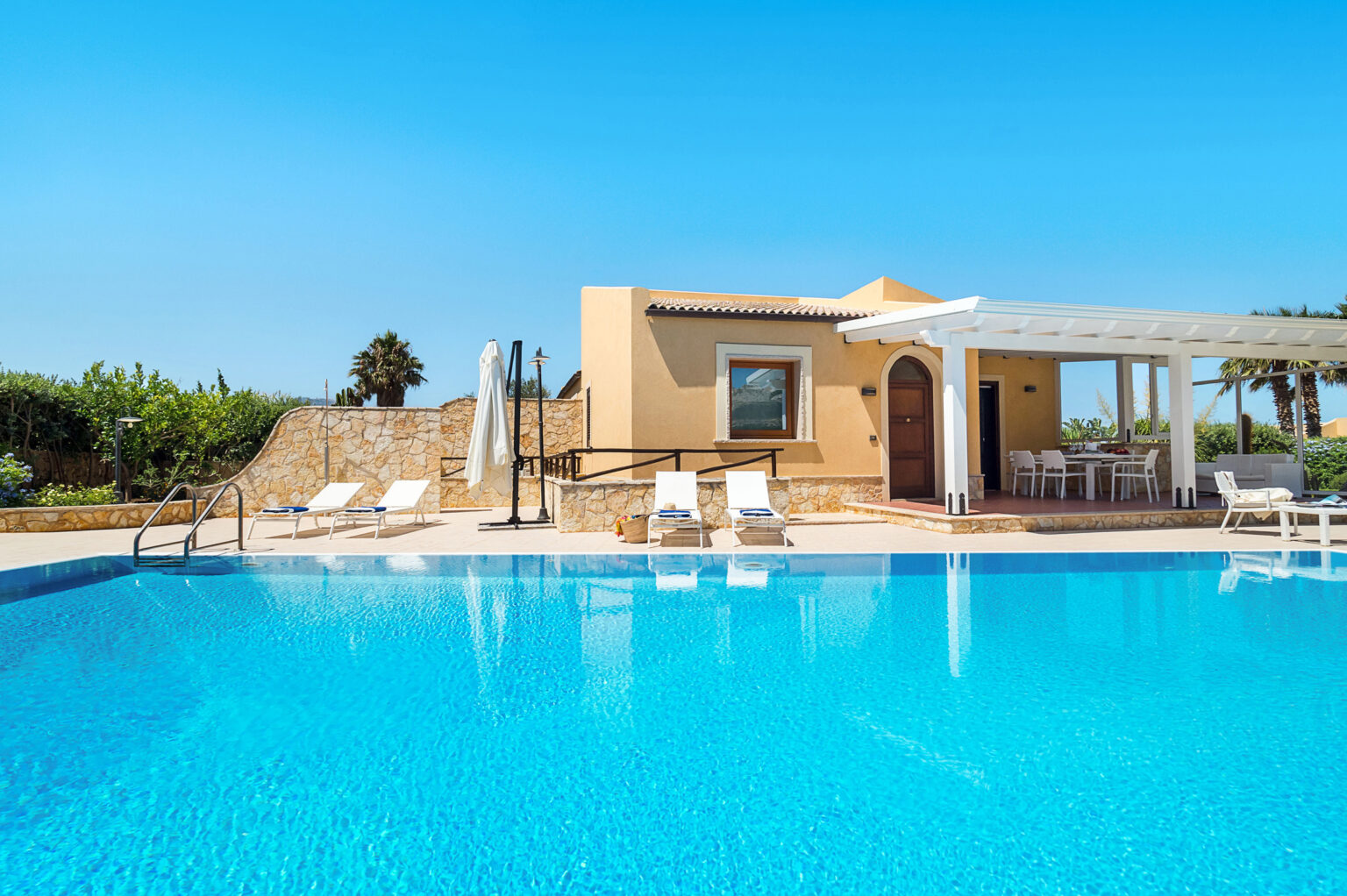 Modern villa with private swimming pool, surrounded by lush greenery and sun loungers, perfect for a relaxing getaway. | Only on SopranoVillas