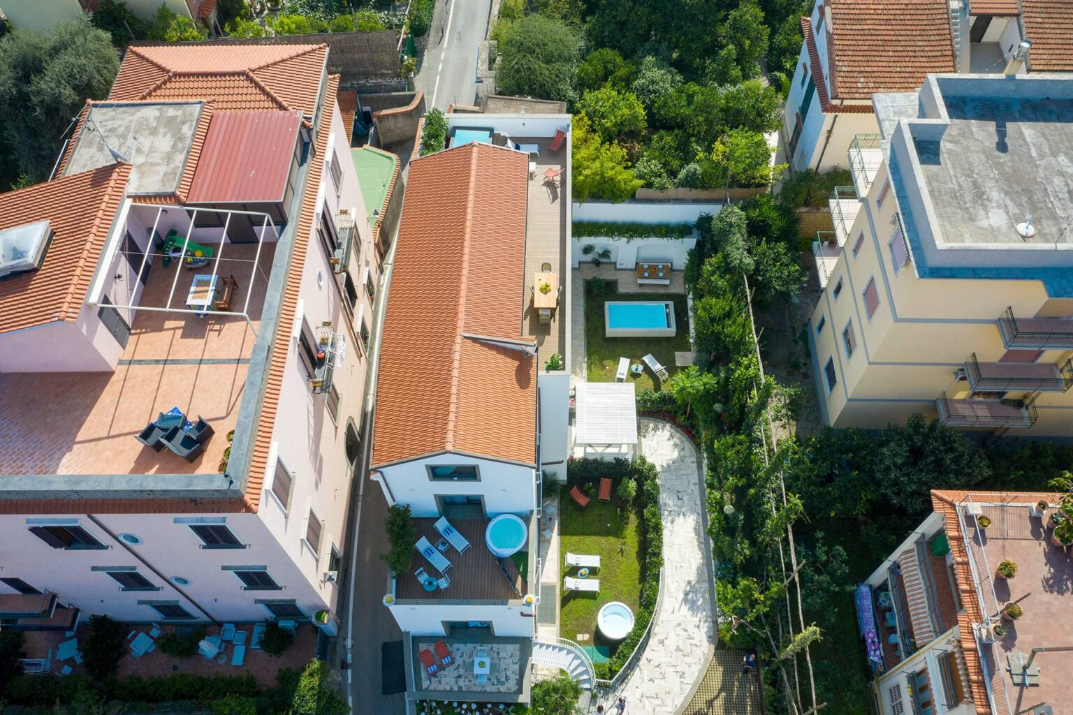 Aerial view of residential buildings featuring a private pool and landscaped garden, surrounded by greenery and modern architecture. | Only on SopranoVillas