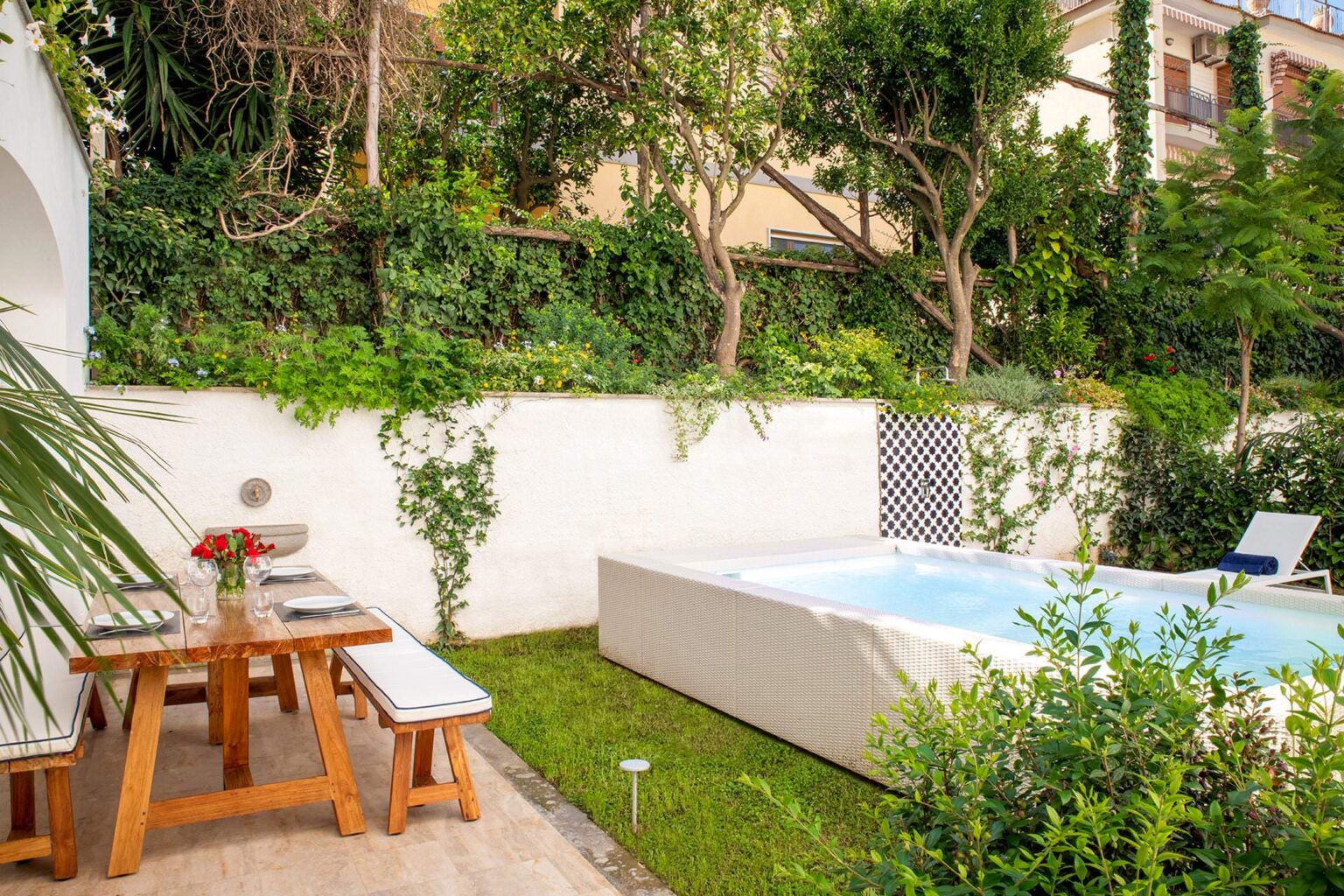Cozy outdoor garden with a dining table and chairs, surrounded by lush greenery, featuring a small private pool for relaxation. Ideal for enjoying a serene outdoor experience. | Only on SopranoVillas