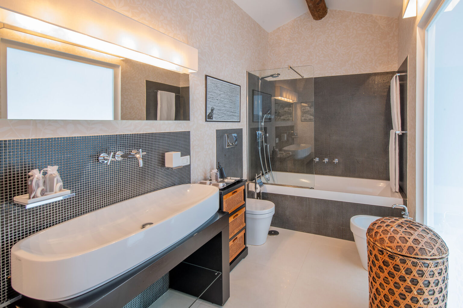 Modern bathroom featuring a sleek, freestanding bathtub, stylish black and white tile design, contemporary fixtures, and ample natural light from a large window. | Only on SopranoVillas