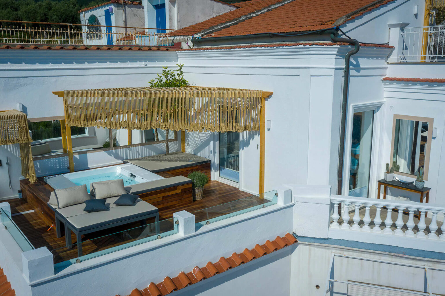 Luxury rooftop terrace featuring a hot tub, comfortable seating, and elegant decor, surrounded by white walls and terracotta tiles, perfect for relaxation and outdoor living. | Only on SopranoVillas