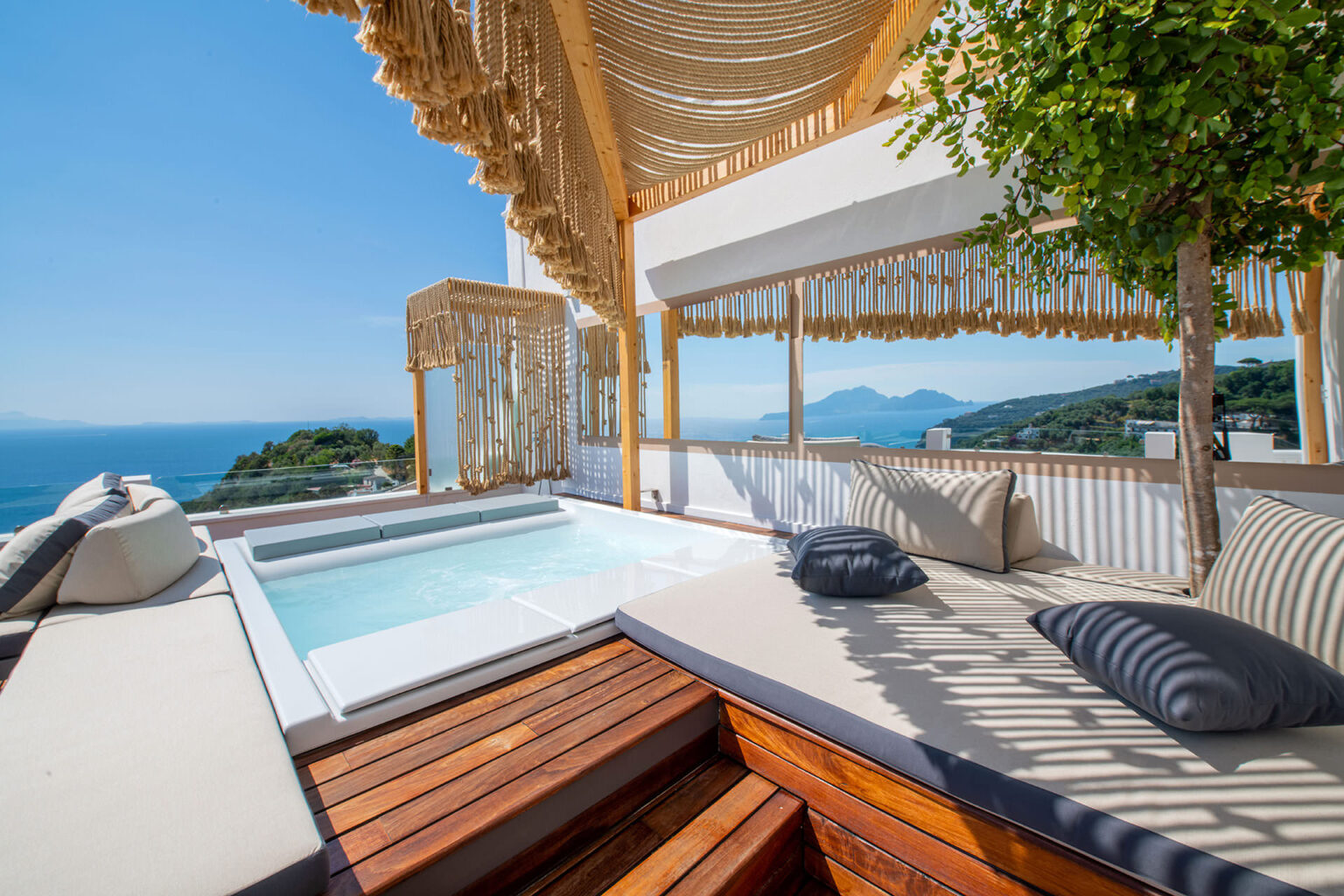 Luxurious outdoor terrace featuring a private jacuzzi, comfortable seating with cushions, and stunning ocean views, perfect for relaxation and leisure. | Only on SopranoVillas