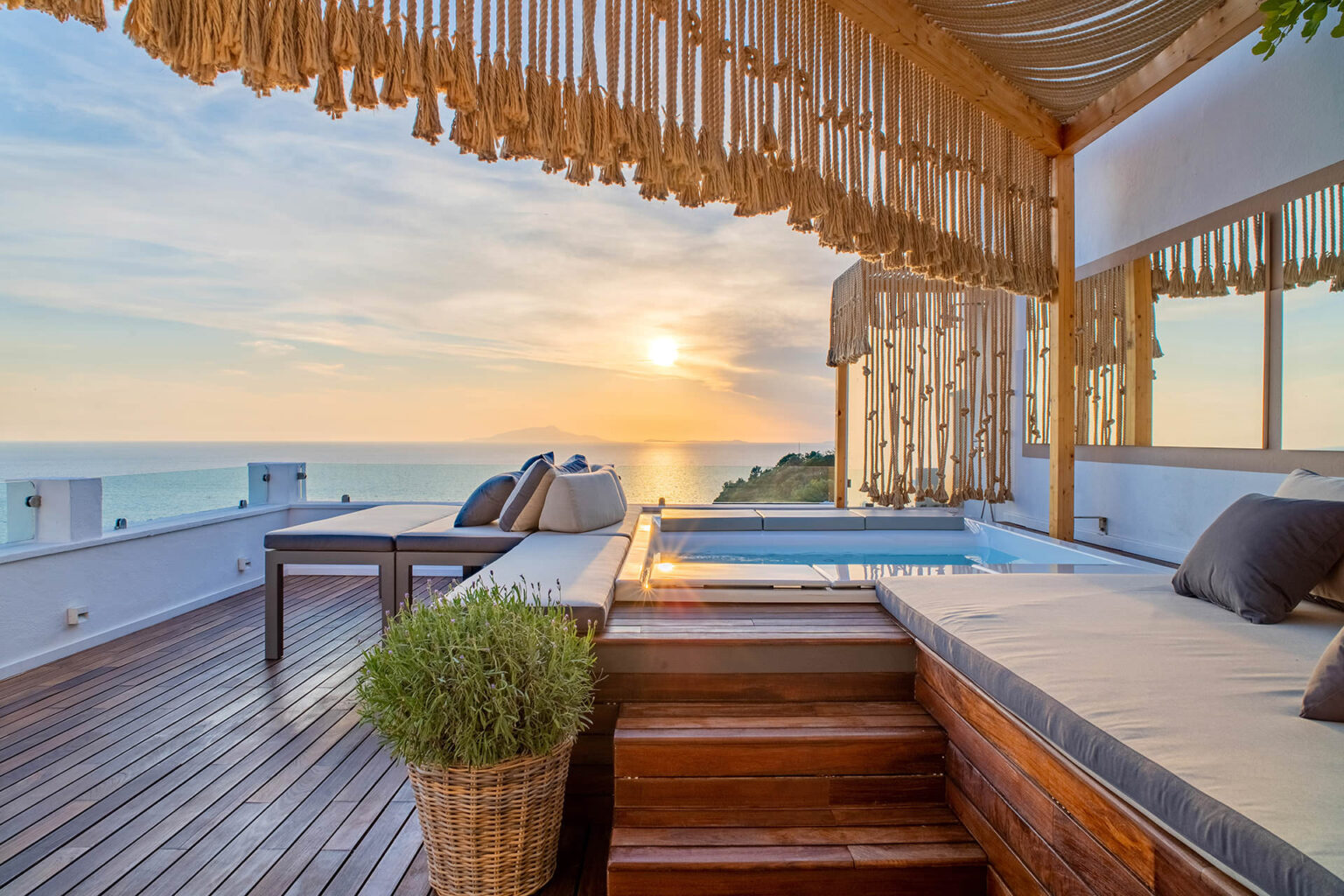 Luxurious outdoor terrace with a sunset view over the ocean, featuring a comfortable seating area, a small plunge pool, and stylish decor elements. Ideal for relaxation and entertainment. | Only on SopranoVillas