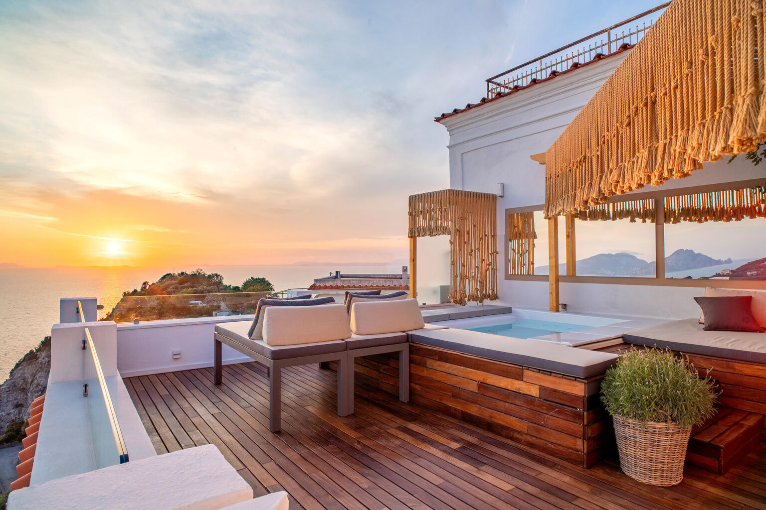 Luxury rooftop terrace with a private hot tub, wooden flooring, and stunning sunset views over the ocean, ideal for relaxation and outdoor living. | Only on SopranoVillas