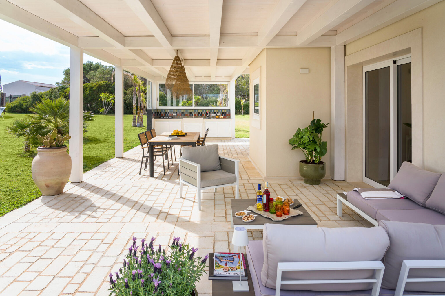 Spacious outdoor patio featuring modern furniture, a dining table with fresh fruit, and lush green landscaping, perfect for entertaining and relaxation. | Only on SopranoVillas