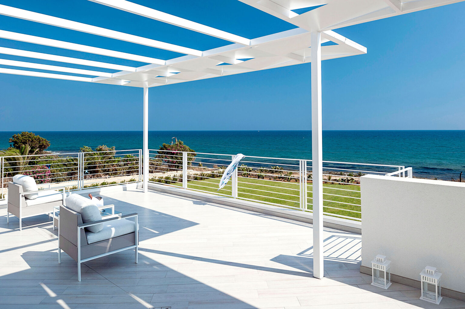 Modern oceanfront terrace with white pergola, stylish outdoor furniture, and stunning sea views, ideal for relaxation and entertaining. | Only on SopranoVillas