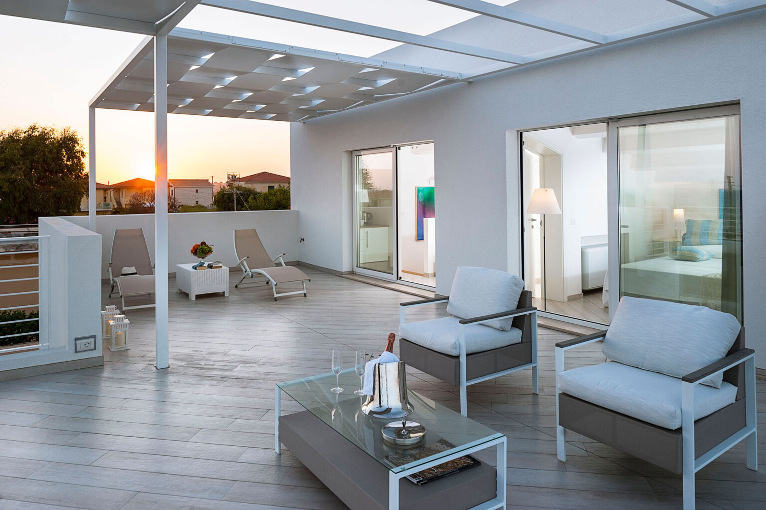 Modern outdoor terrace with stylish seating, a glass table, and a sunset view, featuring a sleek design and spacious layout for relaxation. | Only on SopranoVillas
