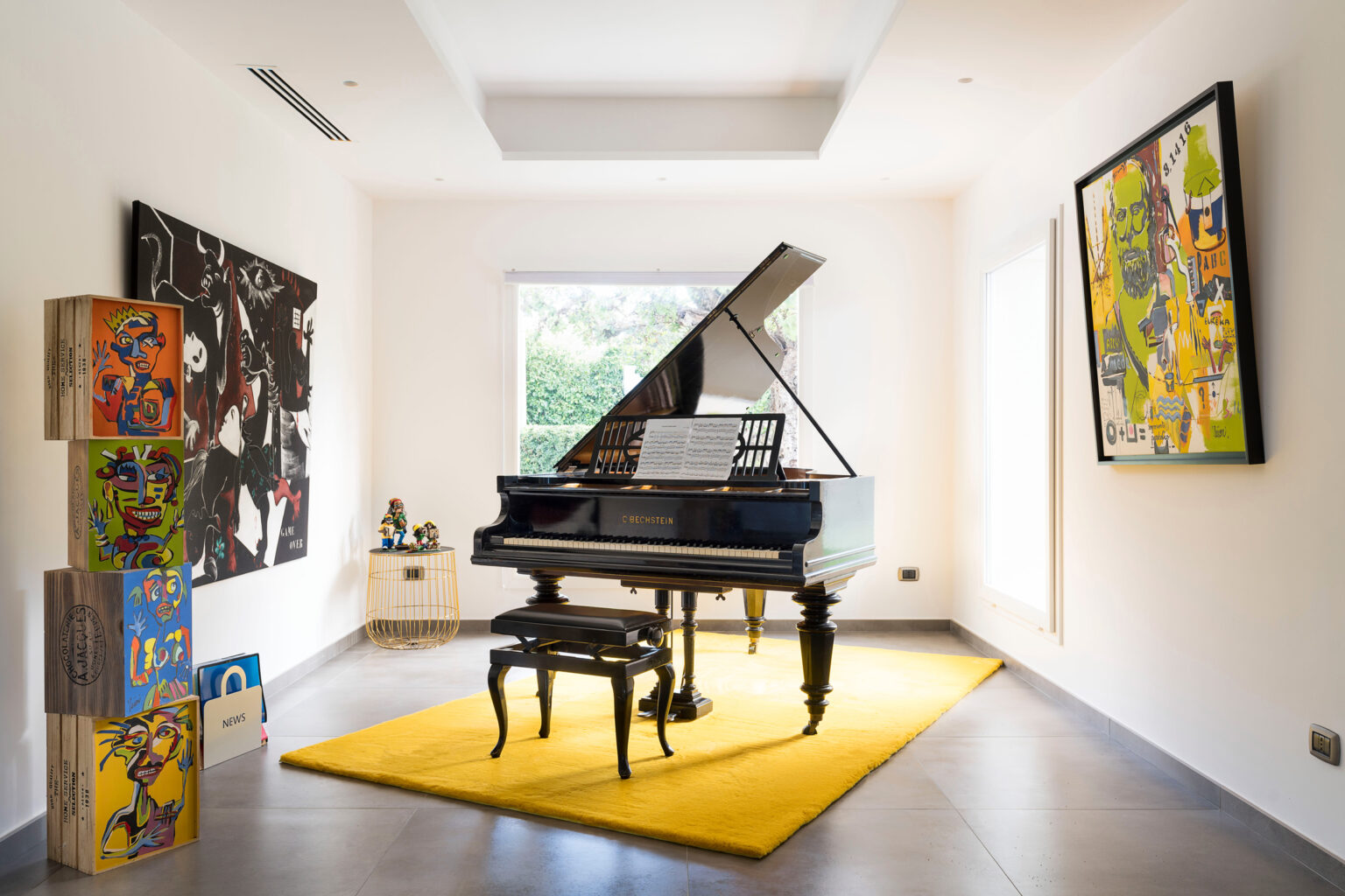 Elegant interior featuring a black Bechstein grand piano on a bright yellow rug, surrounded by contemporary artwork, including colorful paintings and playful sculptures, in a well-lit room with large windows. | Only on SopranoVillas
