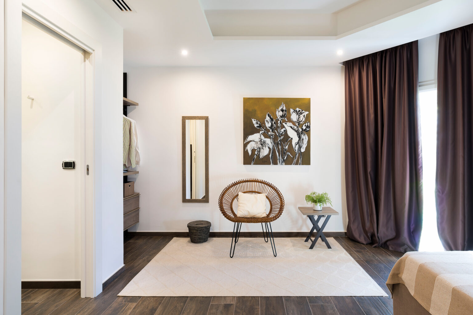 Modern bedroom interior featuring a cozy rattan chair, a small side table, and a decorative painting of flowers on the wall. The room has wooden flooring, soft lighting, and elegant curtains, creating a warm and inviting atmosphere. | Only on SopranoVillas