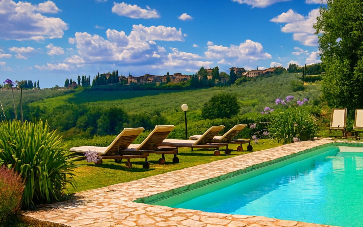 Luxury villa rental in Italy featuring a serene poolside view, sun loungers, and rolling green hills under a blue sky with fluffy clouds, perfect for a relaxing getaway. | Only on SopranoVillas