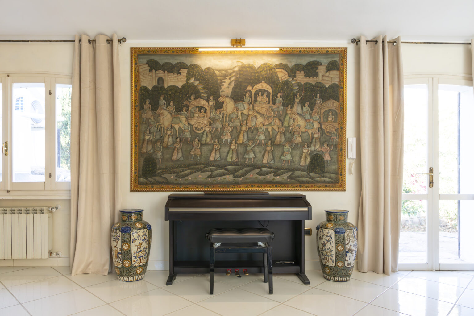 Living room interior featuring a large traditional painting on the wall, a black piano with a matching stool, and decorative vases on either side, complemented by natural light from nearby windows. | Only on SopranoVillas