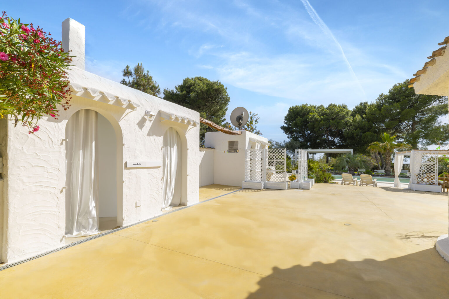 Charming outdoor space featuring whitewashed architecture, a sunny patio, and lush greenery, ideal for relaxation and gatherings. | Only on SopranoVillas