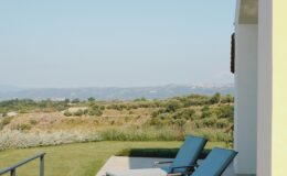 Lounge chairs on a patio overlooking a scenic landscape with rolling hills and clear blue skies, ideal for relaxation and outdoor enjoyment.