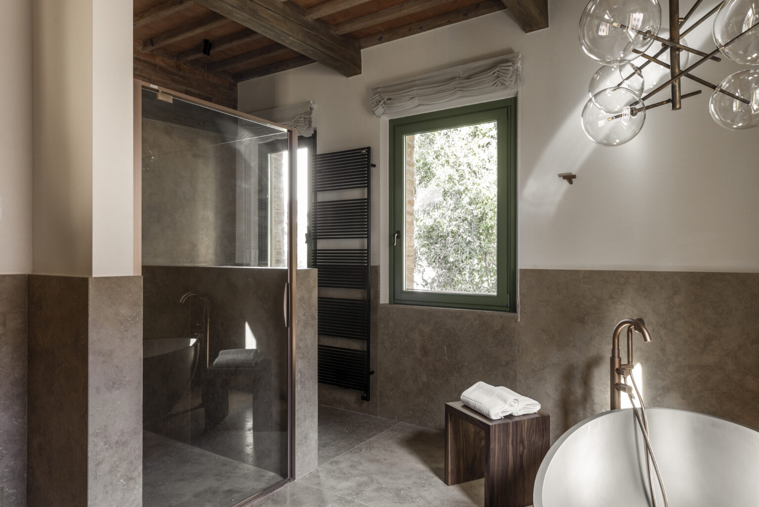 Modern bathroom interior featuring a glass shower, freestanding bathtub, wooden accents, and a large window allowing natural light. The design combines contemporary elements with rustic touches, creating a serene and inviting atmosphere. | Only on SopranoVillas