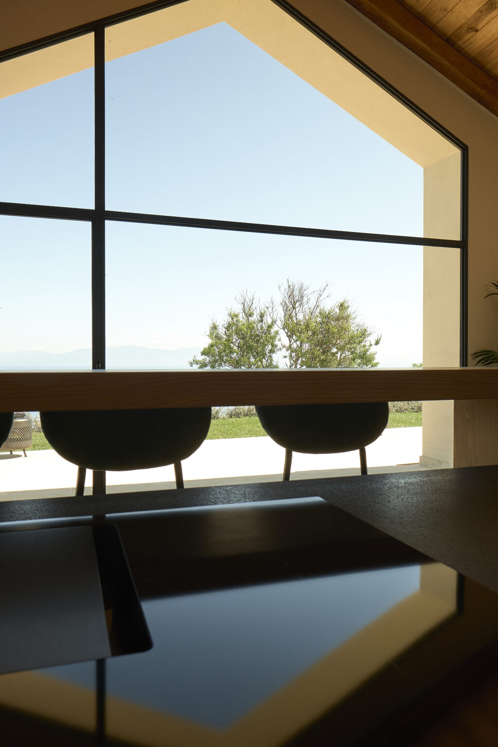 Modern interior view featuring two chairs by a large window, overlooking a serene outdoor landscape with trees and a clear sky. Ideal for showcasing contemporary design and natural light in a living space. | Only on SopranoVillas