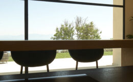 Modern interior view featuring two chairs by a large window, overlooking a serene outdoor landscape with trees and a clear sky. Ideal for showcasing contemporary design and natural light in a living space.
