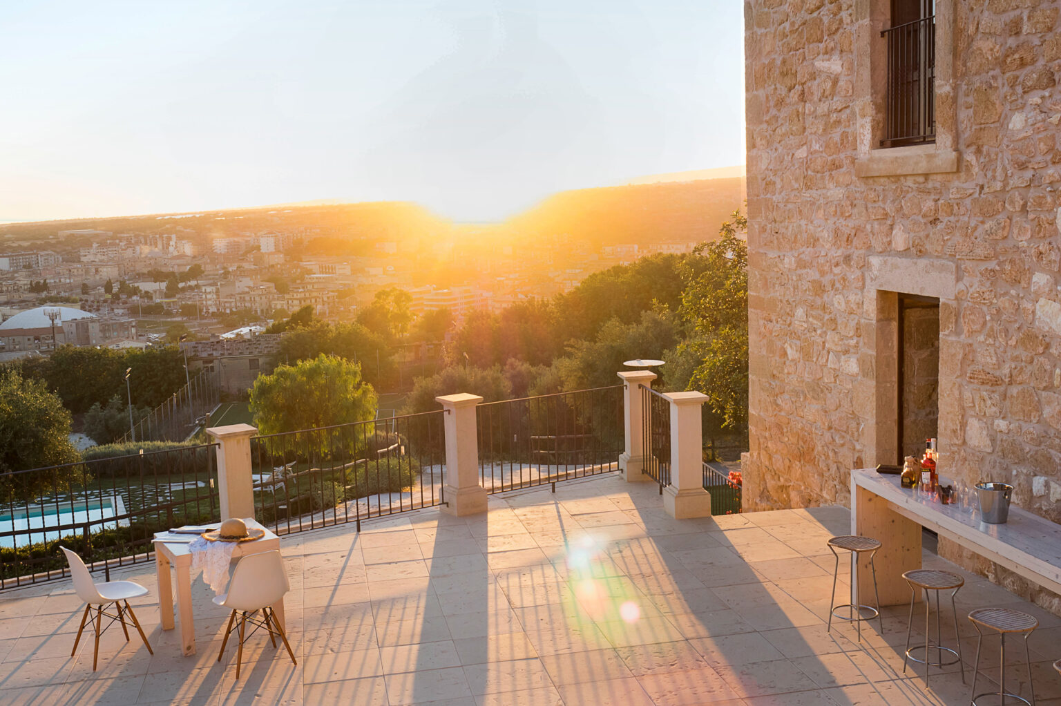 Scenic view of a stone terrace at sunset, featuring outdoor seating and a dining area with a beautiful landscape in the background. Ideal for relaxing or entertaining in a serene environment. | Only on SopranoVillas