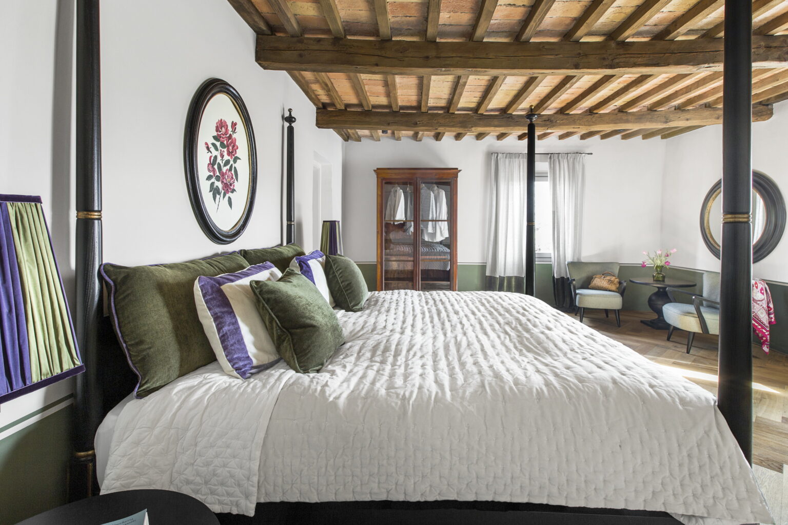 Elegant bedroom featuring a four-poster bed with plush pillows, wooden beams, and stylish decor. The room includes a vintage wardrobe and cozy seating area, creating a warm and inviting atmosphere. | Only on SopranoVillas