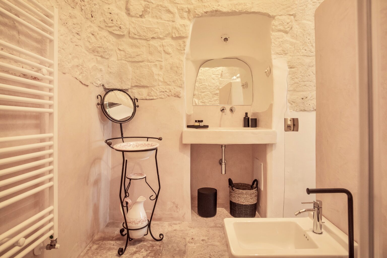 Modern bathroom interior featuring a stone wall, a stylish sink, a mirror on a decorative stand, and contemporary fixtures, creating a warm and inviting atmosphere. | Only on SopranoVillas