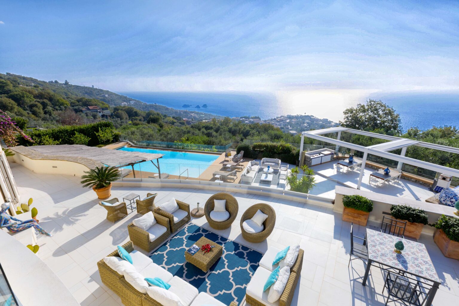 Luxurious villa terrace with ocean view, featuring a swimming pool, stylish outdoor seating, and lush greenery, perfect for relaxation and entertainment. | Only on SopranoVillas