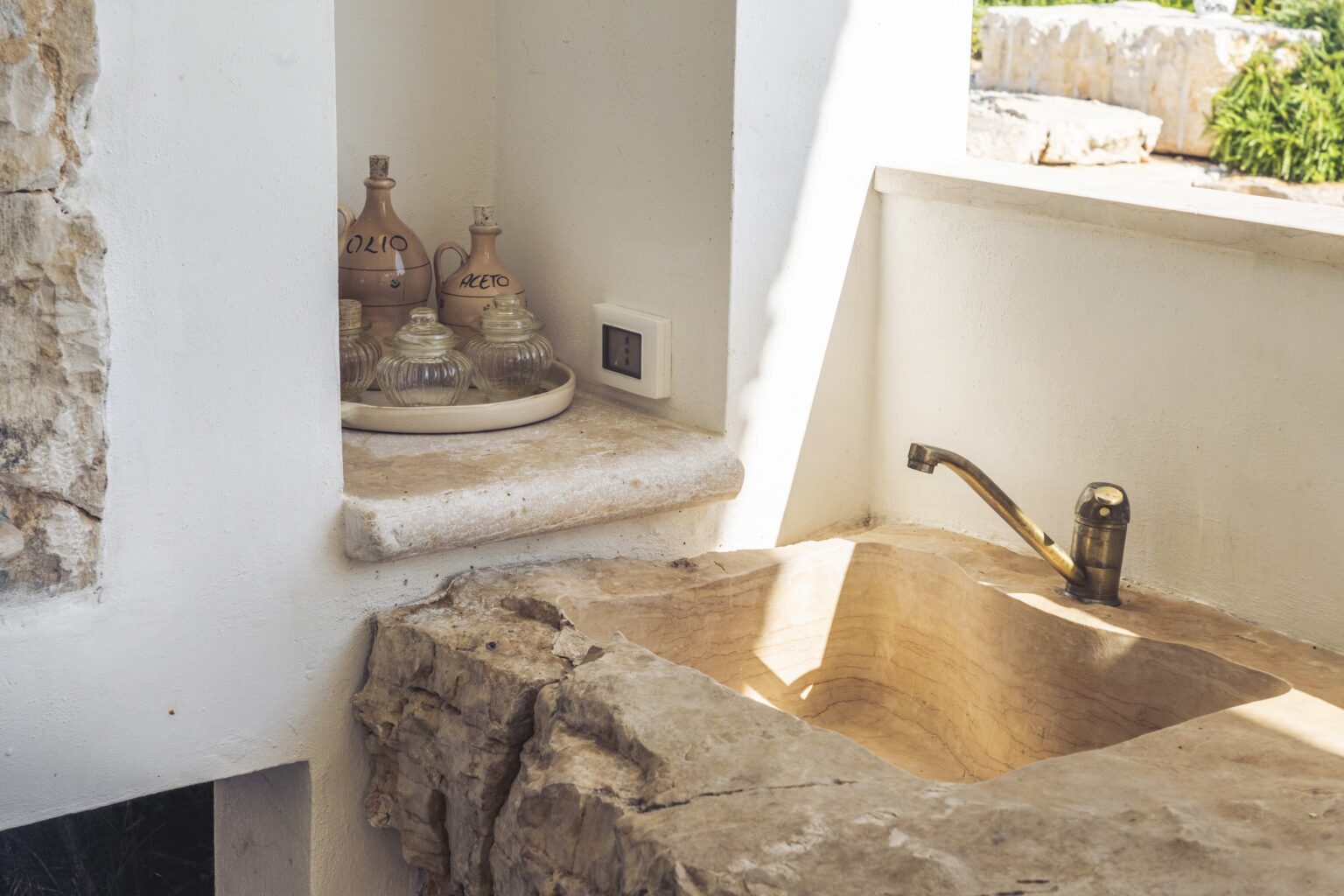 Stylish bathroom design featuring a unique stone sink, natural light, and decorative pottery on a shelf. | Only on SopranoVillas