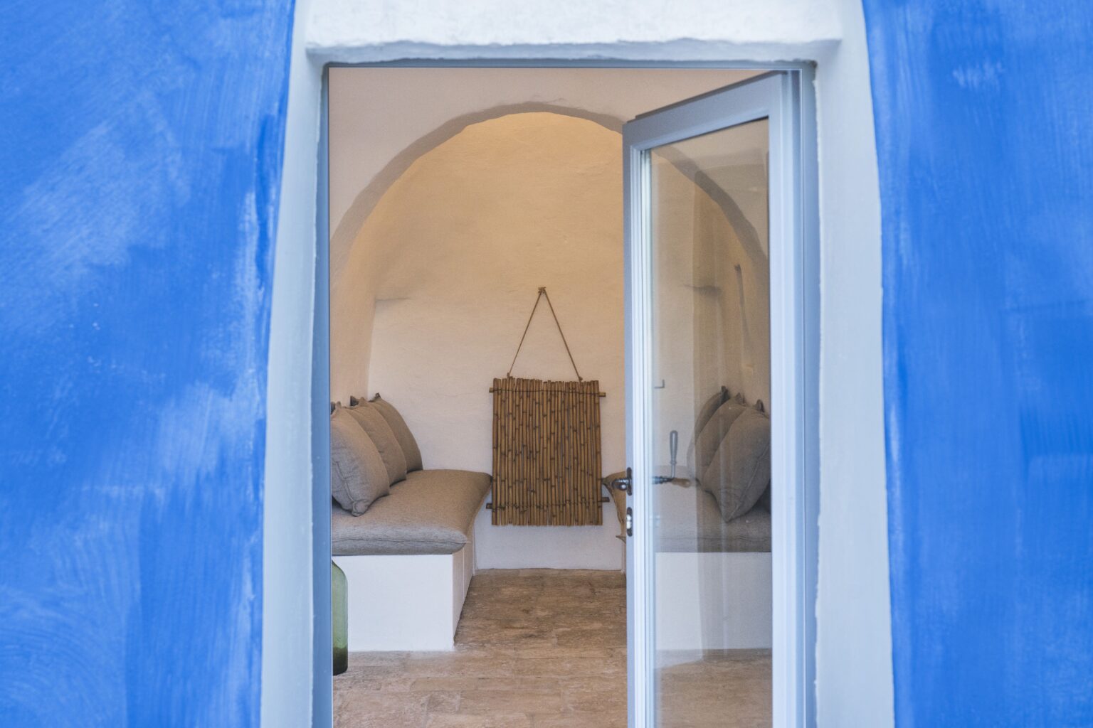 Entrance to a cozy interior with a blue exterior wall, featuring a minimalist design, natural light, and comfortable seating. Ideal for showcasing modern architecture and inviting spaces. | Only on SopranoVillas